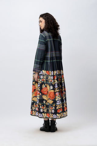 Woman wearing a plaid coat over a floral dress on a white background